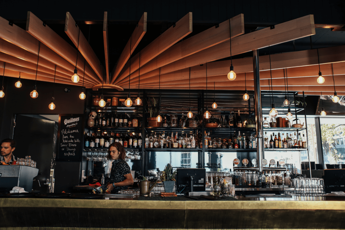 People in restaurant bar area where beverages are displayed 