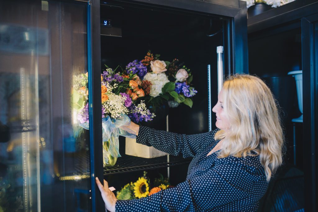 Image of a women arranging flowers in a commercial floral cooler