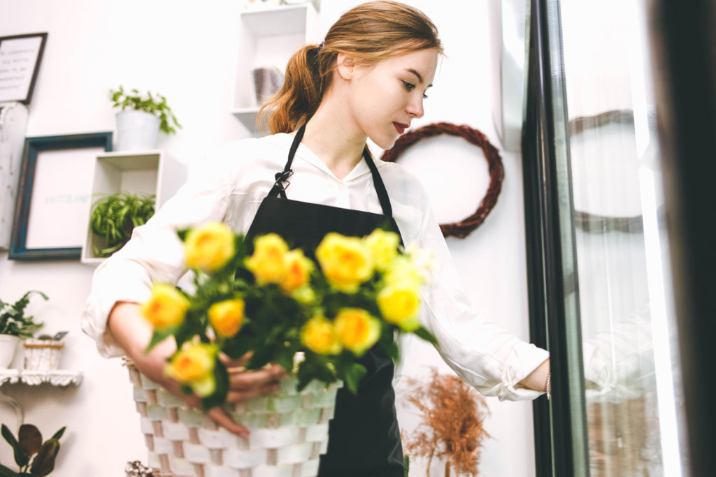 A women is arranging flowers inside the floral refrigerator